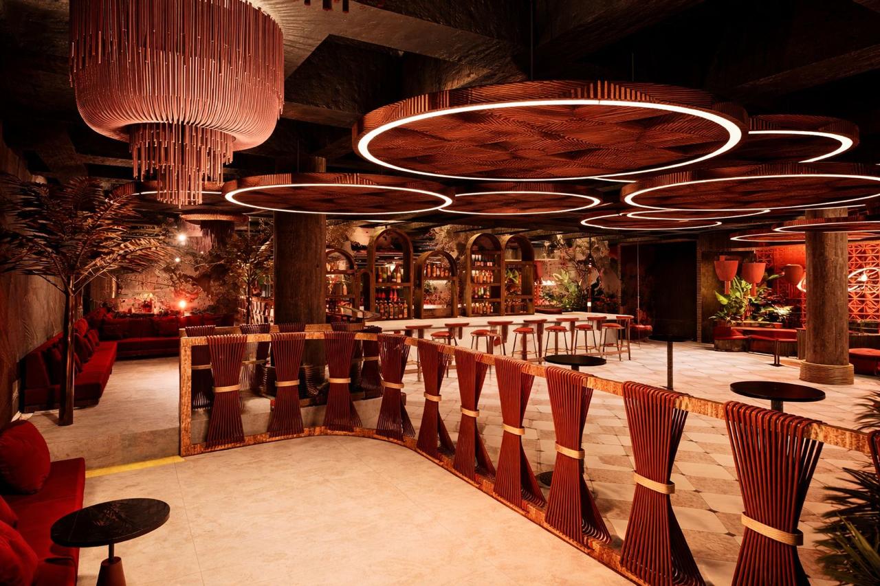 The Candela lounge — red banquettes, ring chandeliers and woven balustrade