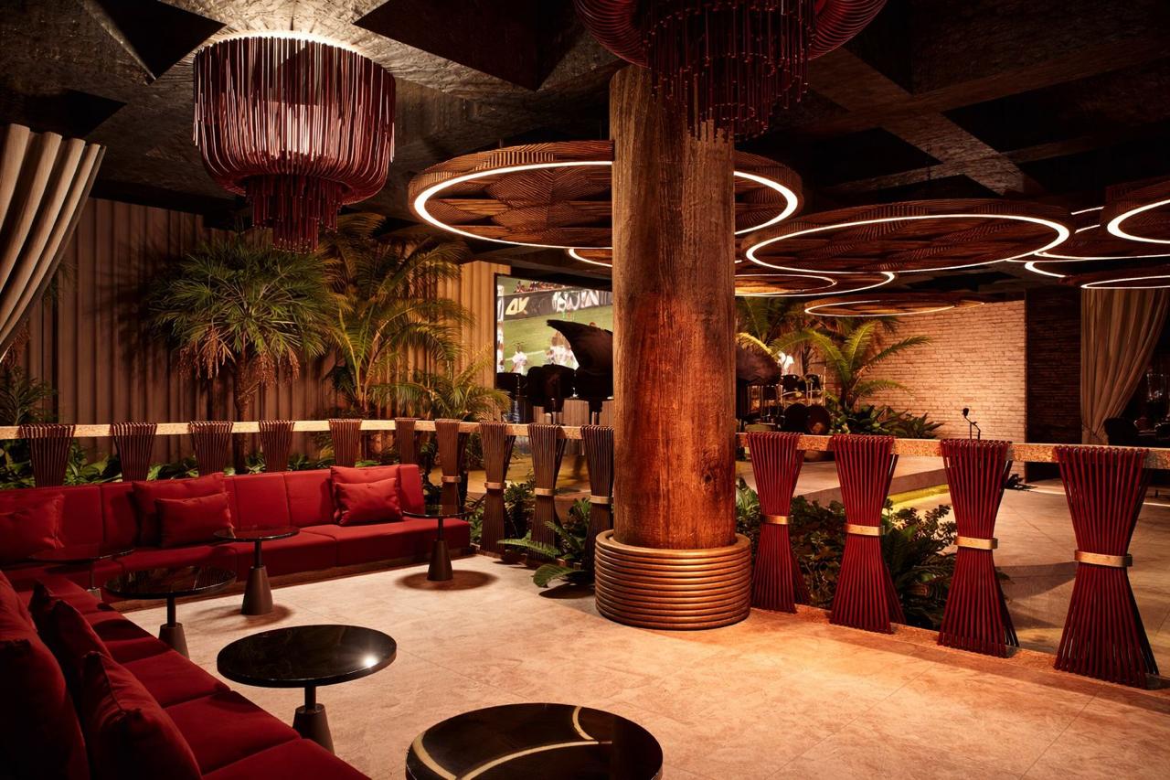 The Candela lounge seating — red velvet sofas around a timber column