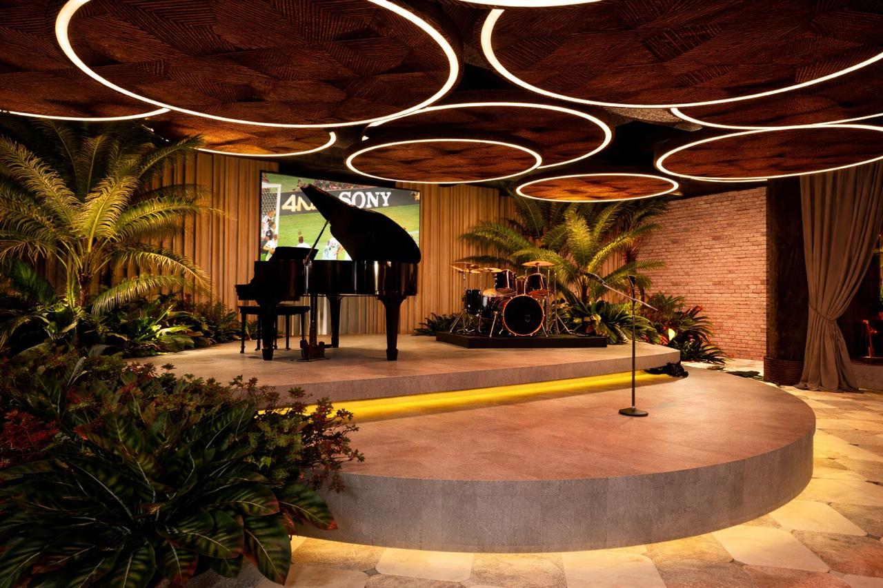 The Candela stage — grand piano and drums beneath ring lighting and palms